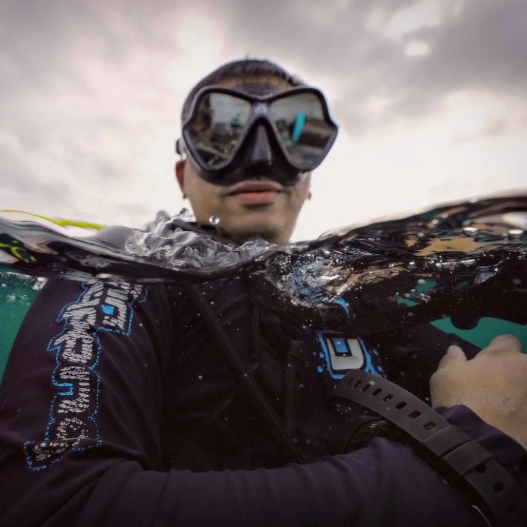 Hardik at the water surface in a dive mask, the waterline cutting across the frame