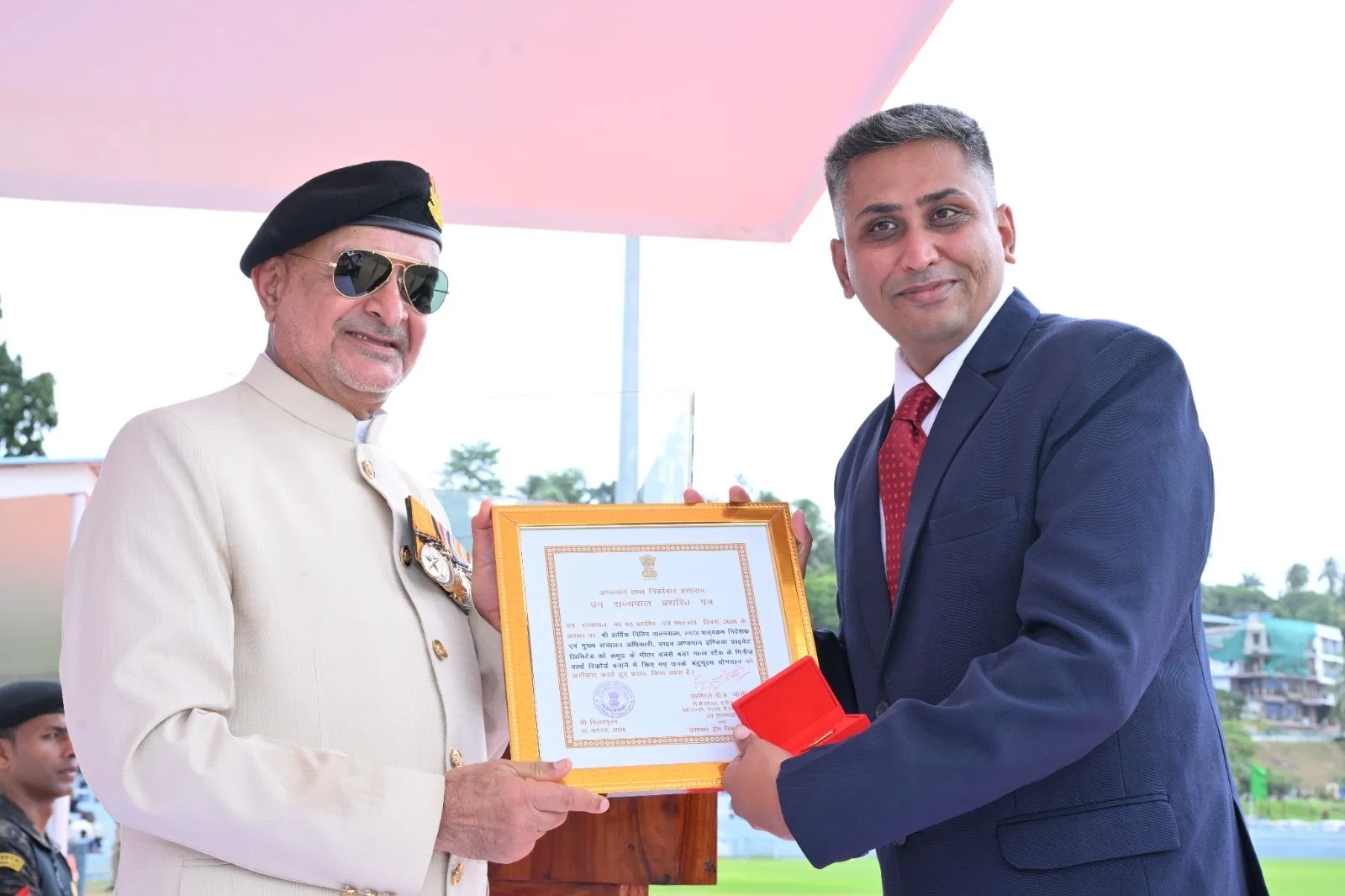 The Lieutenant Governor of the Andaman and Nicobar Islands presenting the framed commendation and medal to Hardik Datanwala on the ceremony dais