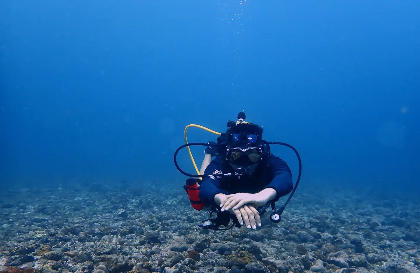 Hardik hovering in neutral buoyancy over a rocky reef in open blue water
